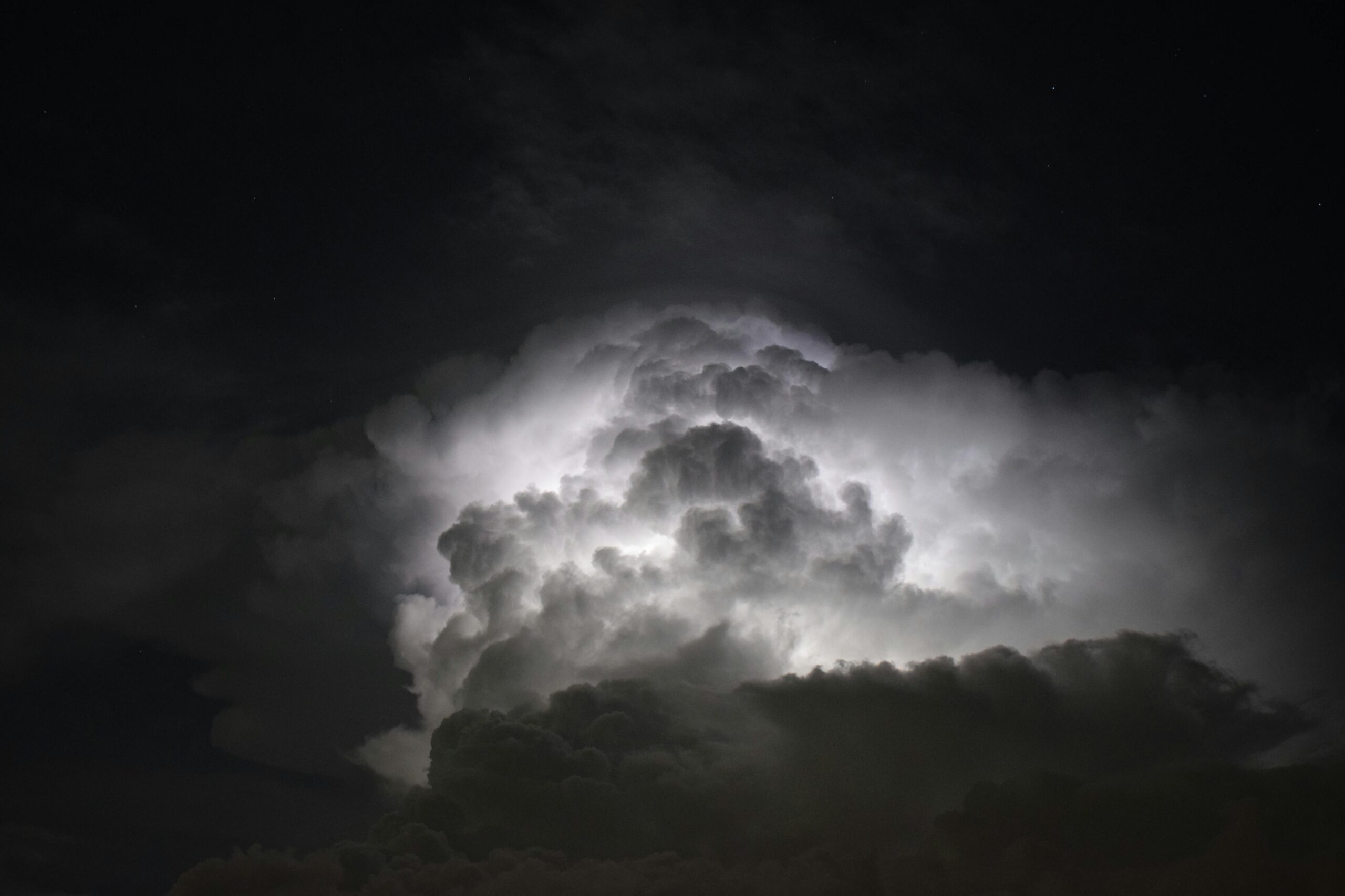 Powerful lightning illuminates dark storm clouds at night, creating a dramatic and mysterious sky.